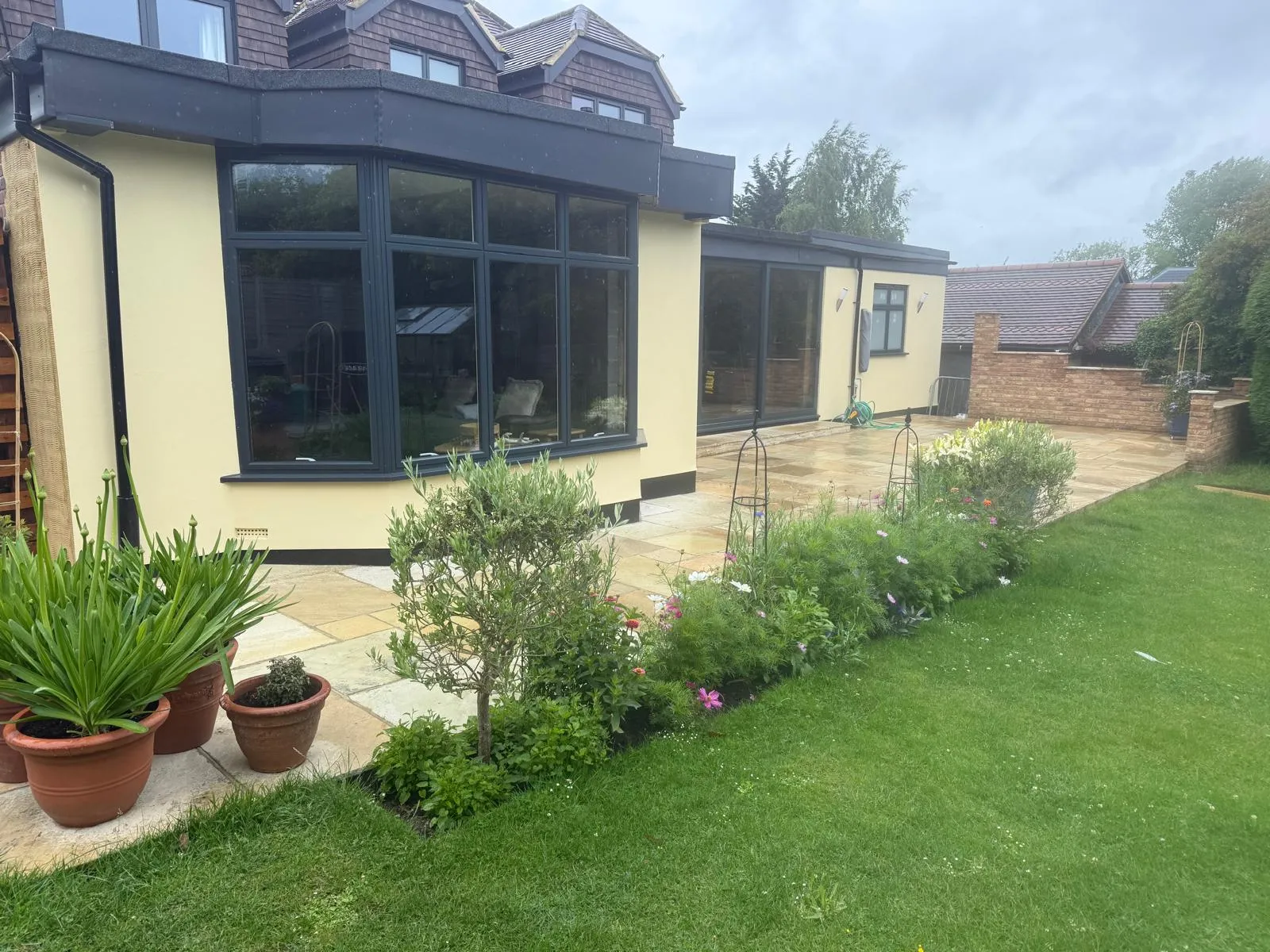 Indian sandstone patio edged with a freshly planted border and lawn in Downe Village