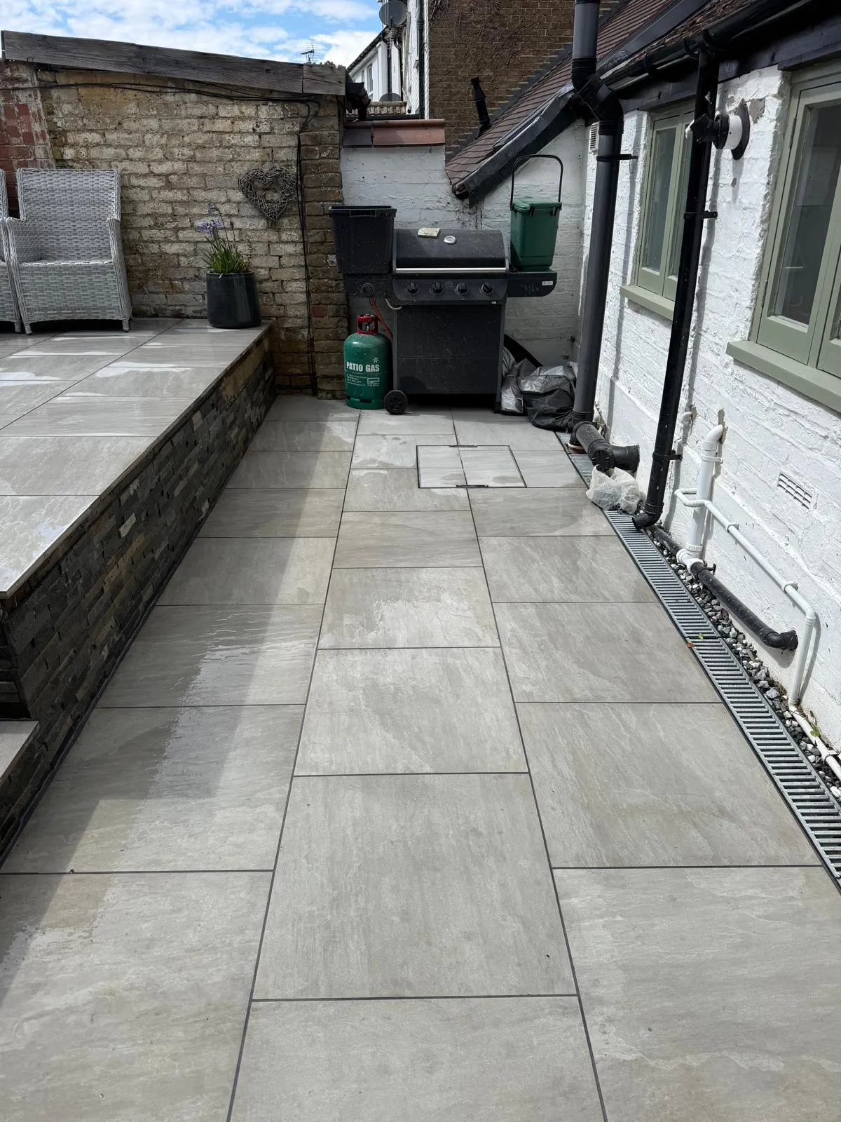 Grey porcelain side path with a drainage channel alongside a rendered house in Farnborough Village
