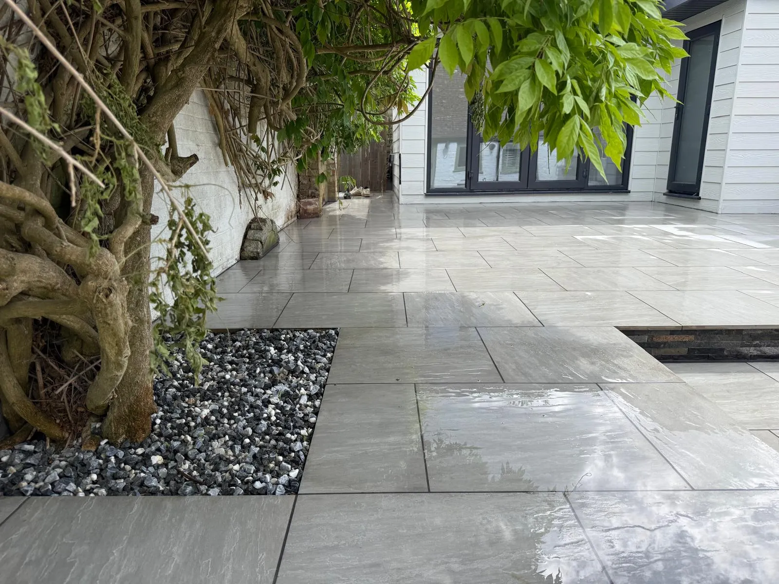 Grey porcelain paving with a slate-grey pebble border beside anthracite doors in Farnborough Village