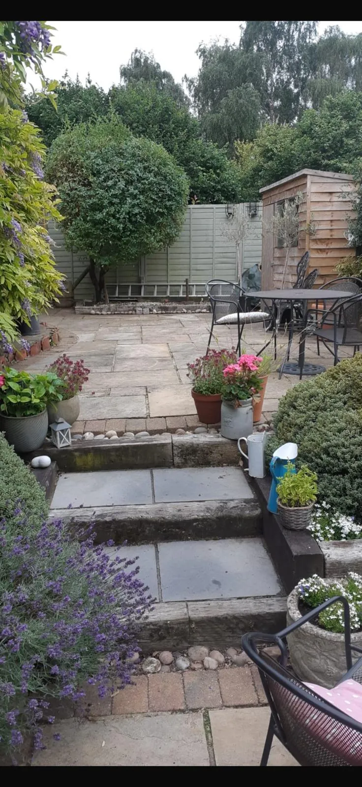 Split-face stone steps and grey porcelain paving with potted planting in a Farnborough Village garden