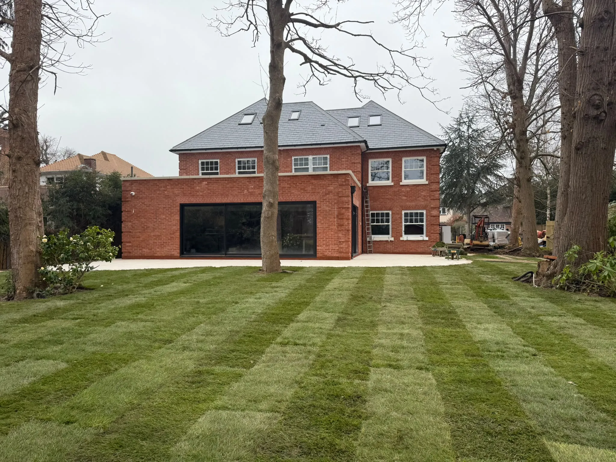 Freshly laid striped lawn behind a large home turfed by Prestige Landscapes