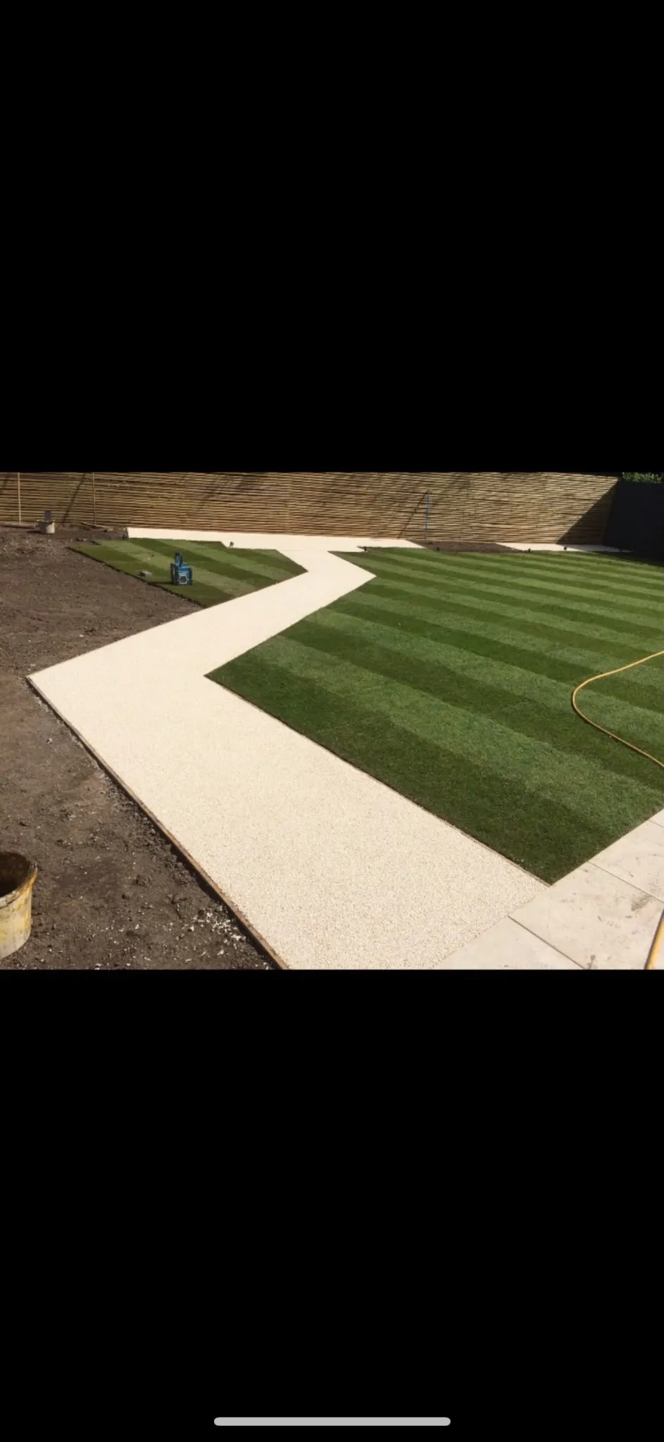 Winding resin-bound path between striped lawns laid by Prestige Landscapes