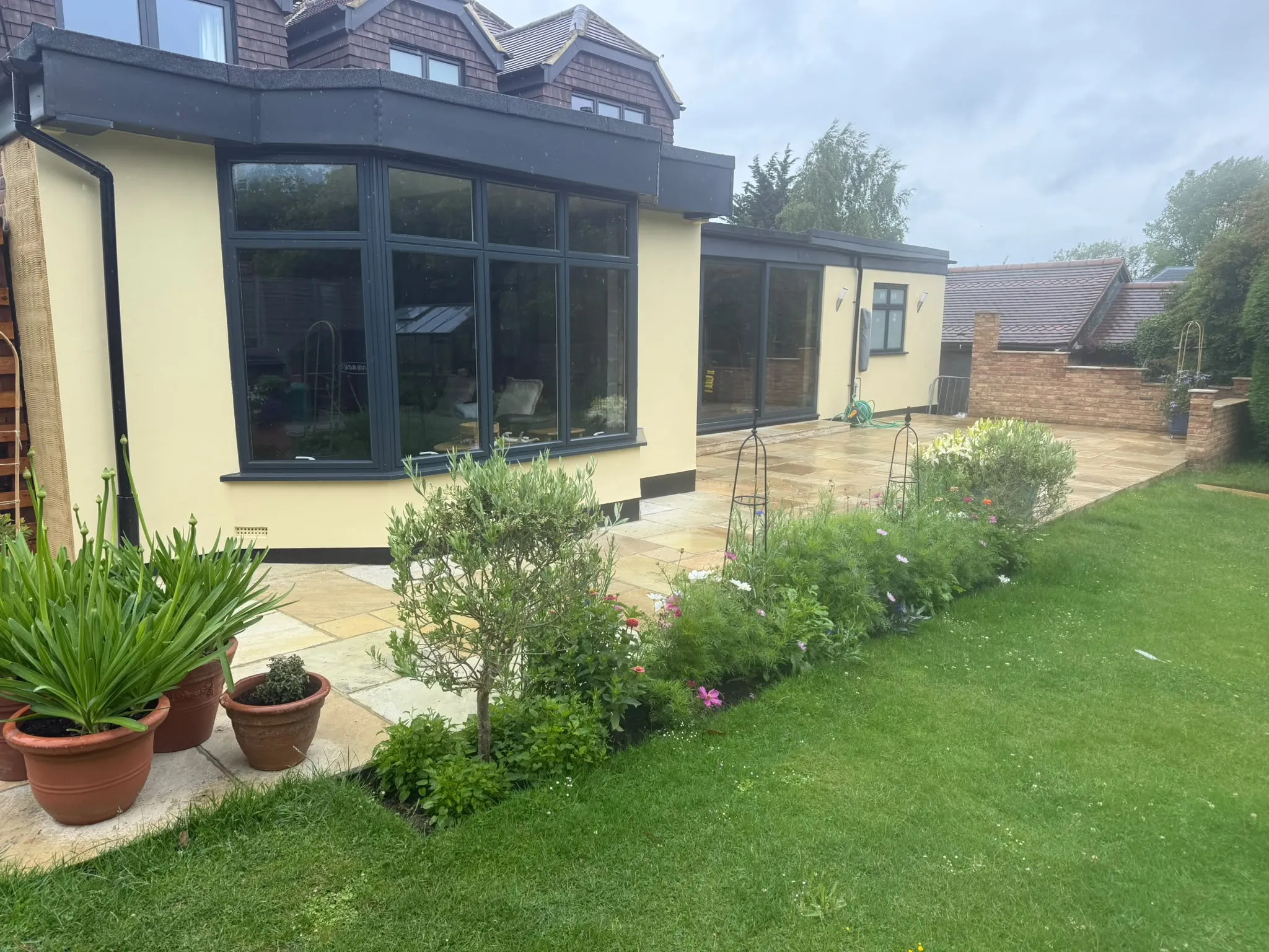 Indian sandstone patio with planted borders by Prestige Landscapes