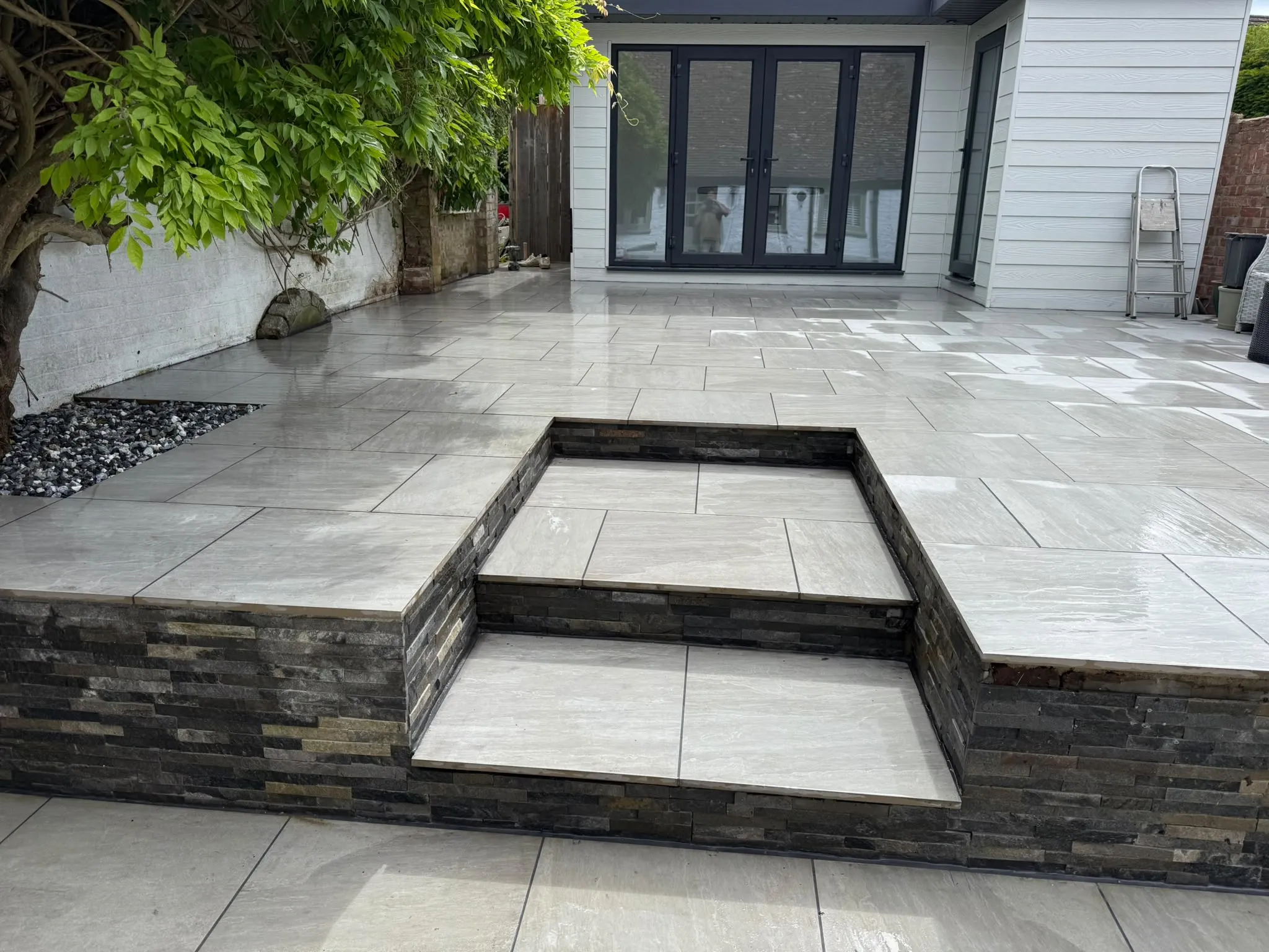 Grey porcelain patio with split-face stone steps by Prestige Landscapes