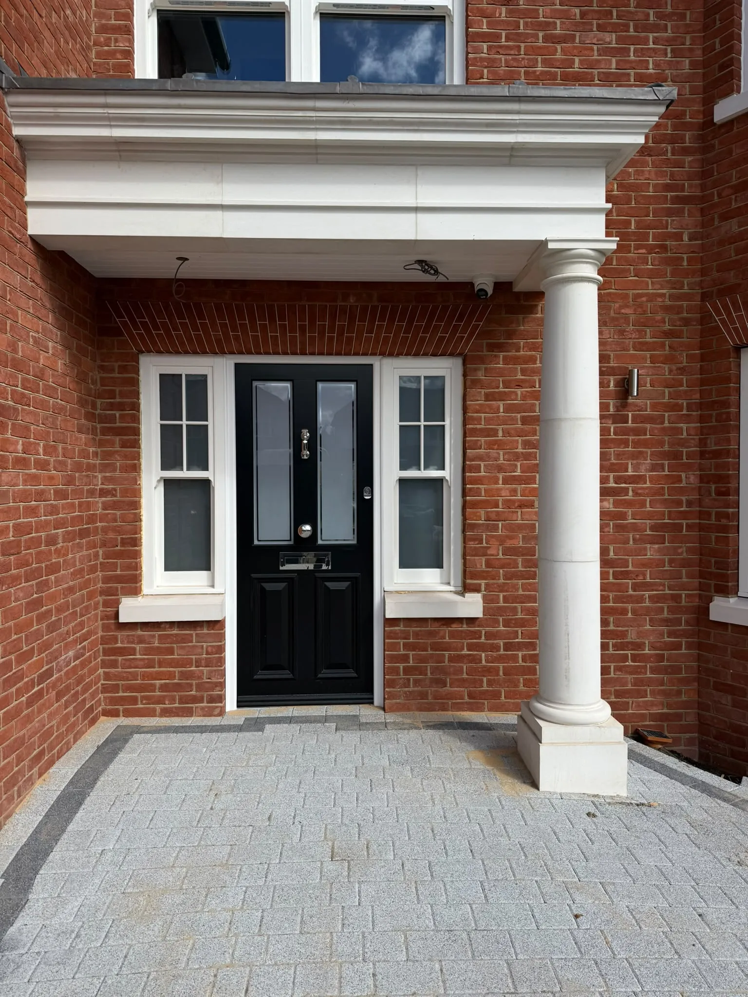 Front entrance with stone portico and block paving by Prestige Landscapes