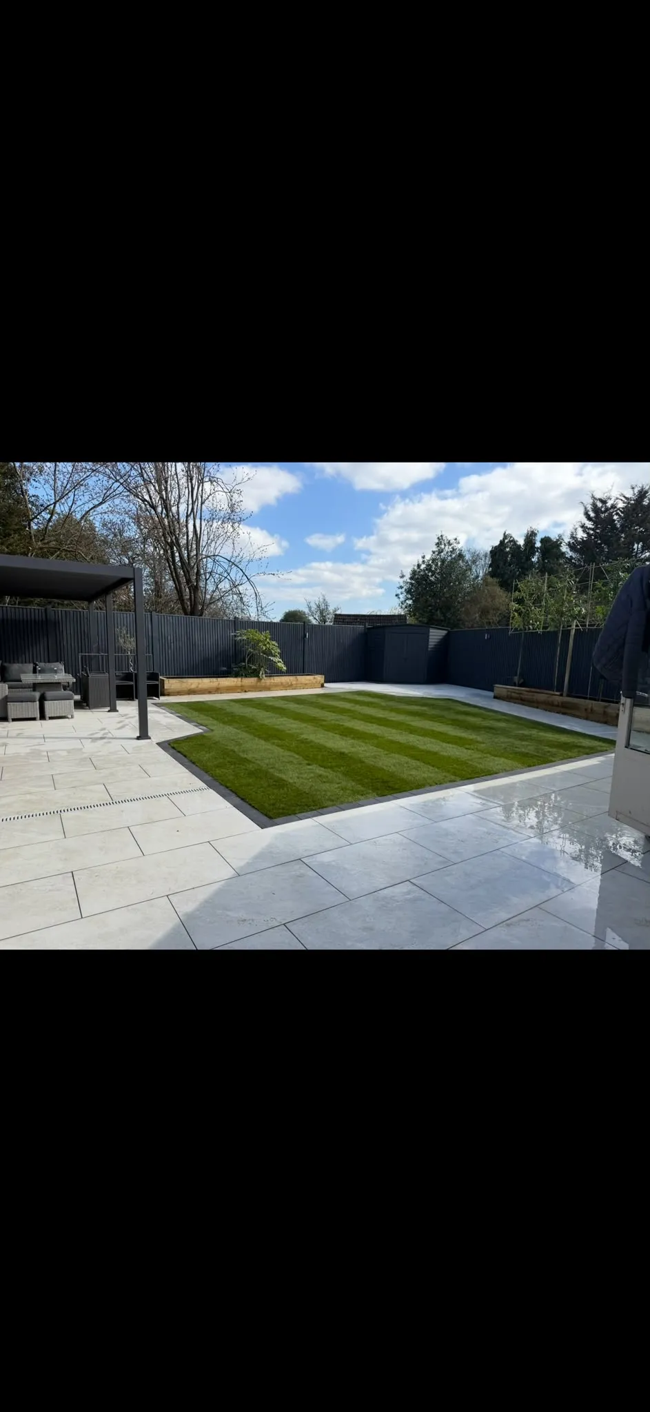 Light porcelain patio framing a striped lawn garden design by Prestige Landscapes