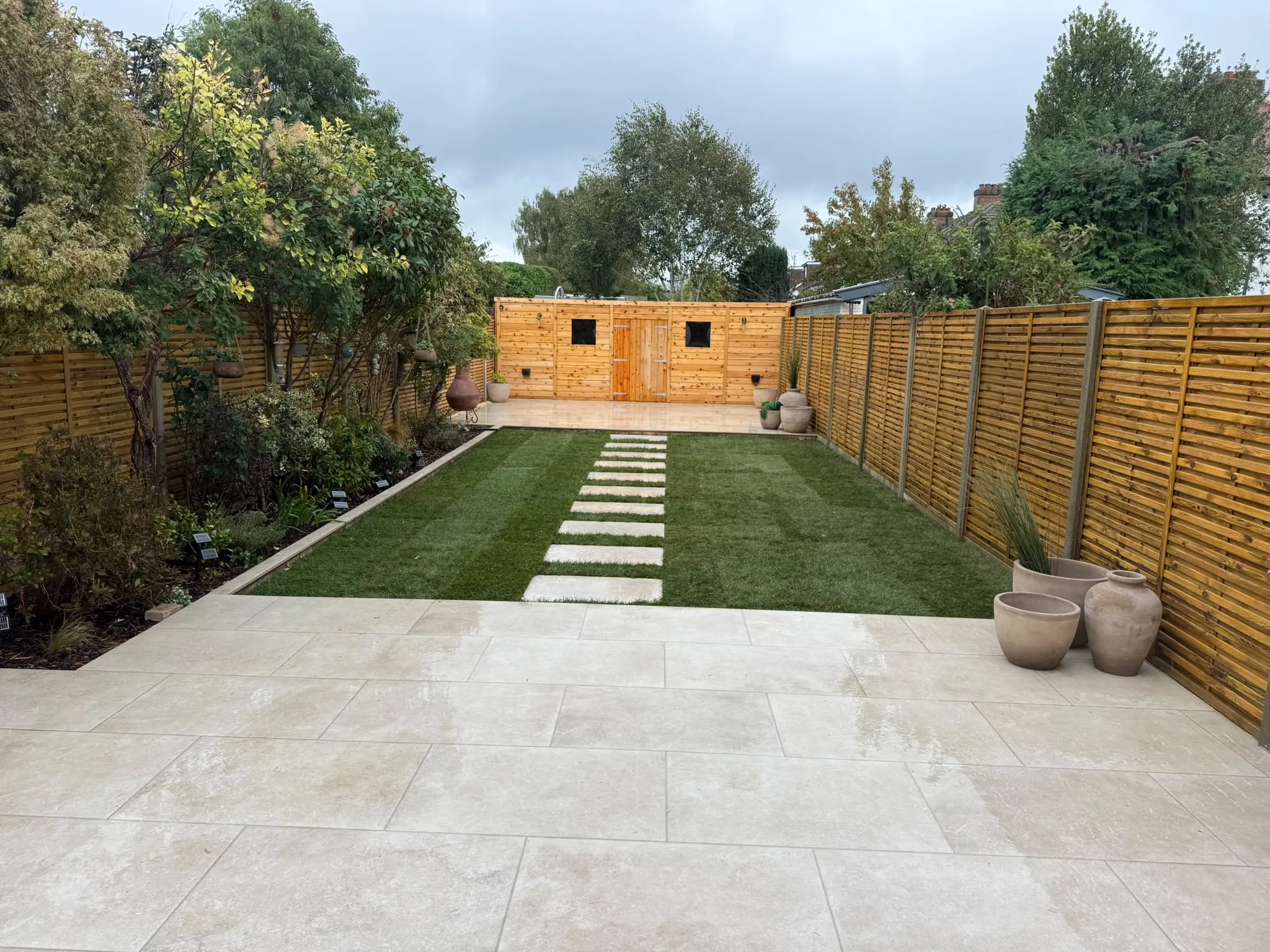 Finished Beckenham garden refurbishment with porcelain patio, artificial lawn and garden room by Prestige Landscapes