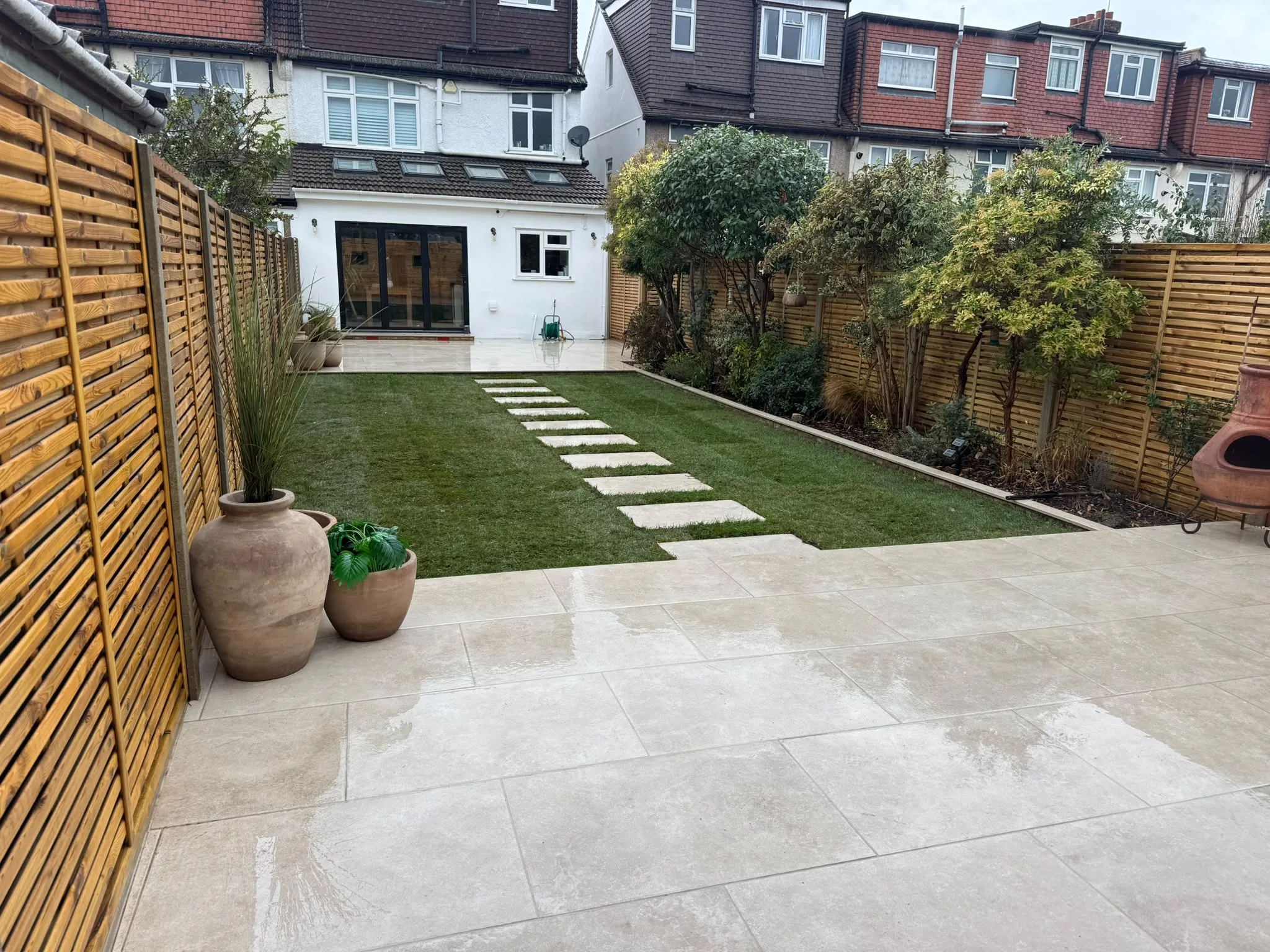 Finished Beckenham garden looking to the house, with porcelain patio and artificial lawn by Prestige Landscapes